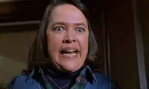 Kathy Bates con occhi sbarrati e bocca aperta in una scena di un film. La sua espressione suggerisce terrore o sorpresa.