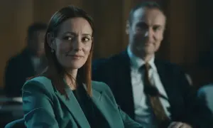 Donna con tailleur verde acqua sorride, mentre un uomo in giacca e cravatta la osserva. Forse stanno discutendo del codice da un miliardo di dollari.