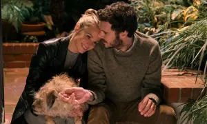 Coppia affettuosa con un cane, scena che ricorda i film e programmi TV di Adam Brody.