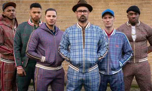 Il cast di The Gentlemen posa con completi a quadri coordinati, pronti per un'avventura.