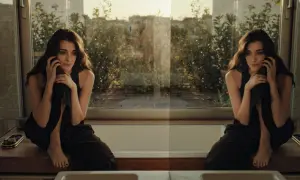 Una donna pensierosa al telefono, seduta su un davanzale con vista su un giardino. Un momento sospeso, forse l'inizio di una breve storia d'amore.