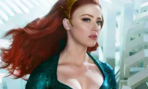 Amber Heard in un film, con lunghi capelli rossi e un diadema dorato, indossa un abito verde acqua.