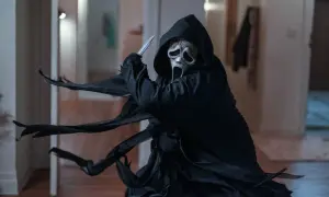 Ghostface, icona del film di Scream, brandisce un coltello con la sua maschera spettrale e il mantello svolazzante.