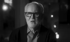 Primo piano in bianco e nero di John Lithgow con occhiali, che riflette sulla sua carriera nei film e programmi TV.