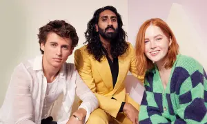 Amar Chadha Patel, con un completo giallo, posa con due giovani attori.