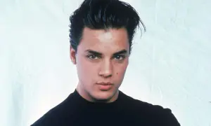 Ritratto di Nick Kamen, un giovane uomo con capelli scuri pettinati all'indietro e un maglione nero. La sua espressione è seria, mentre si riflette sulla sua **malattia**.