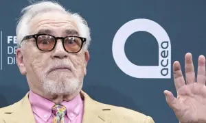 Brian Cox, noto per i suoi film e programmi TV, con occhiali e cravatta colorata.