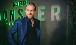 Charlie Hunnam, protagonista di film e programmi TV, posa con un sorriso davanti al logo Netflix.