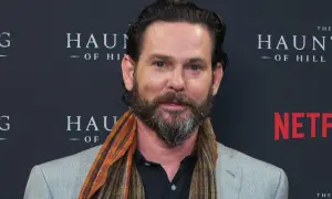 Henry Thomas, noto per i suoi film e programmi TV, sorride con una sciarpa colorata.