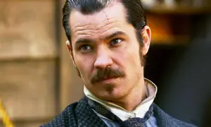 Timothy Olyphant, con cicatrice sulla fronte, baffi e basette, in abiti d'epoca, un volto iconico dei suoi film e programmi TV.