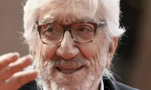Ritratto di Gigi Proietti, con barba e capelli bianchi, occhiali da vista. La sua morte ha lasciato un vuoto nel cuore di molti.