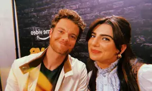 Jack Quaid sorride con la sua fidanzata, una foto scattata davanti a uno sfondo con il logo di Amazon.