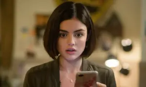 Lucy Hale, protagonista di film e programmi TV, guarda sorpresa il suo telefono.