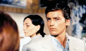 Alain Delon, icona di stile, in una scena che evoca i suoi film più belli. Sguardo intenso, fascino intramontabile.