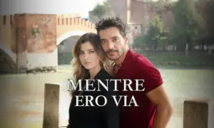 Coppia abbracciata con un ponte sullo sfondo. Il titolo "Mentre ero via" suggerisce una storia di assenza e ritorno.