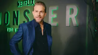 Charlie Hunnam, protagonista di film e programmi TV, posa con un sorriso davanti al logo Netflix.