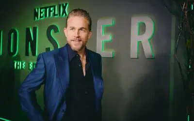 Charlie Hunnam, protagonista di film e programmi TV, posa con un sorriso davanti al logo Netflix.