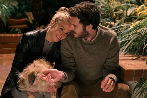 Coppia affettuosa con un cane, scena che ricorda i film e programmi TV di Adam Brody.