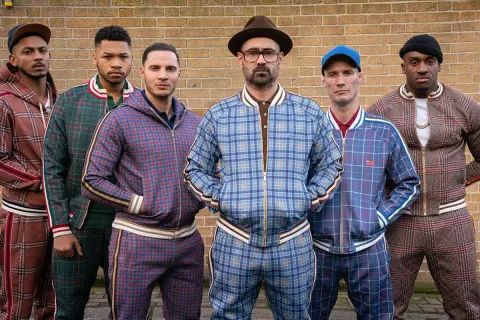 Il cast di The Gentlemen posa con completi a quadri coordinati, pronti per un'avventura.