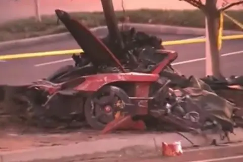 Resti di un'auto rossa distrutta, scena di un tragico incidente che ricorda la paul walker morte. Nastro giallo di delimitazione.