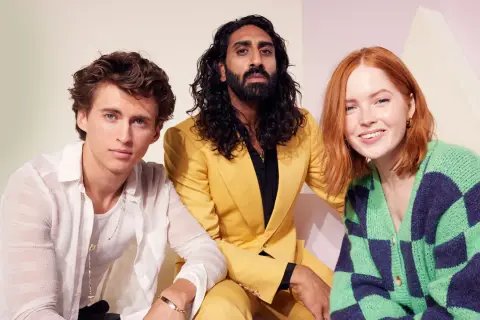 Amar Chadha Patel, con un completo giallo, posa con due giovani attori.