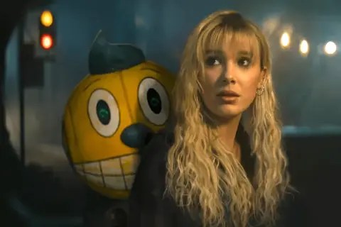 Ragazza bionda con un personaggio giallo dietro, in un'atmosfera cupa. Sembrano in uno stato elettrico di tensione.