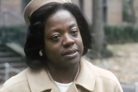 Viola Davis, con un cappello e un cappotto beige, in una scena di film e programmi TV.