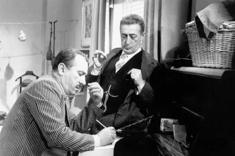 Totò e Peppino, nel cast di "La Malafemmina", discutono animatamente. Uno scrive, l'altro gesticola.