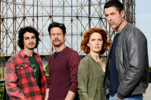Il cast di "Io ti cercherò" posa davanti a una struttura metallica.