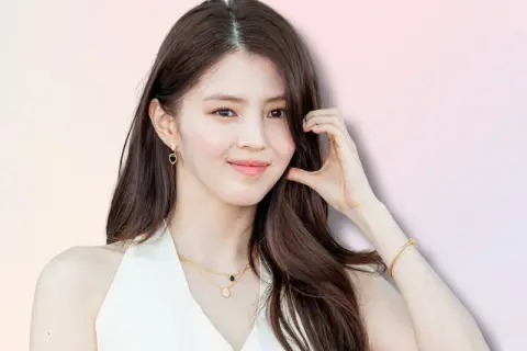 Han So Hee, con capelli castani lunghi, indossa orecchini a goccia e una collana d'oro.