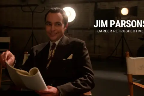 Jim Parsons, in un abito elegante, sfoglia un copione. Un omaggio ai suoi film e programmi TV.