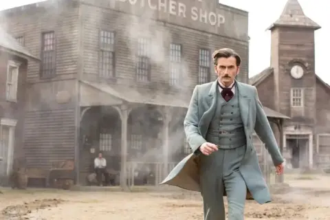 Phileas Fogg, protagonista de "il giro del mondo in 80 giorni serie tv", cammina in un villaggio polveroso.