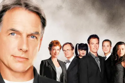 Mark Harmon in primo piano, circondato dal cast di film e programmi TV di NCIS.