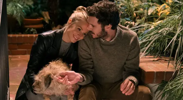 Coppia affettuosa con un cane, scena che ricorda i film e programmi TV di Adam Brody.