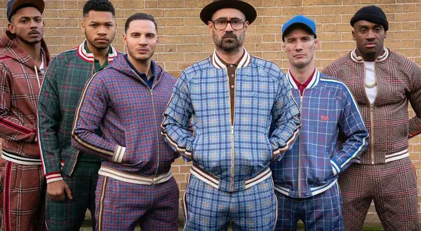 Il cast di The Gentlemen posa con completi a quadri coordinati, pronti per un'avventura.