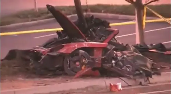 Resti di un'auto rossa distrutta, scena di un tragico incidente che ricorda la paul walker morte. Nastro giallo di delimitazione.