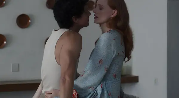 Jessica Chastain in un film, vicina a un uomo con capelli ricci. Lei indossa un vestito azzurro con motivi rossi.