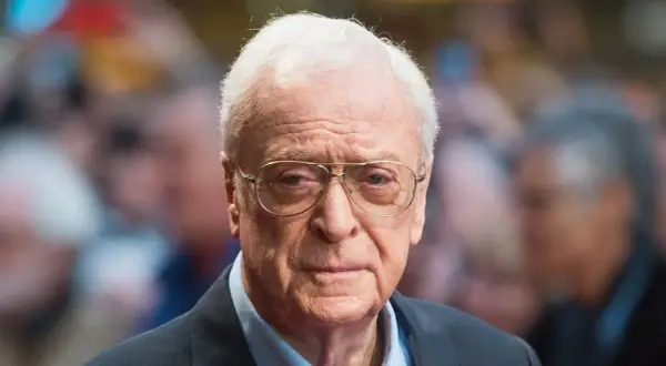 Michael Caine, icona del cinema, con occhiali e sguardo intenso. Un volto che ha segnato tanti film indimenticabili.