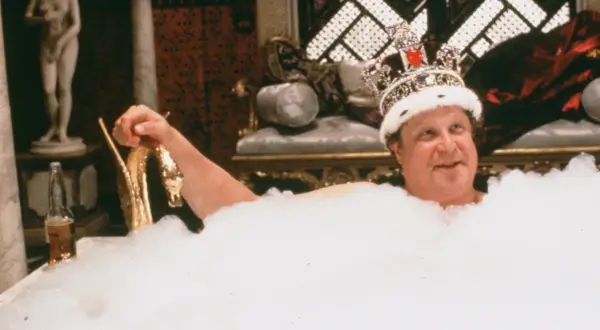 Un uomo con una corona scintillante, immerso in una vasca piena di schiuma, sorride. Sembra che sua maestà viene da Las Vegas, pronto per un bagno regale.