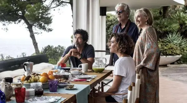 Una famiglia riunita per una colazione all'aperto, tra risate e sguardi pensierosi. Un momento di gioia e riflessione, una vera croce e delizia.