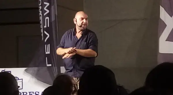 Giovanni Cacioppo, con un microfono all'orecchio, parla a un pubblico. La sua storia sulla malattia ispira.