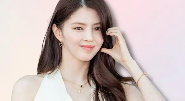 Han So Hee, con capelli castani lunghi, indossa orecchini a goccia e una collana d'oro.
