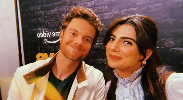 Jack Quaid sorride con la sua fidanzata, una foto scattata davanti a uno sfondo con il logo di Amazon.