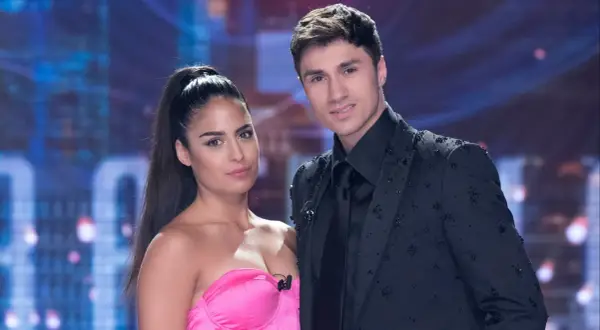 Mirko e Perla, un duo affascinante sul palco, lei con un abito rosa acceso, lui elegante in giacca nera tempestata di cristalli.