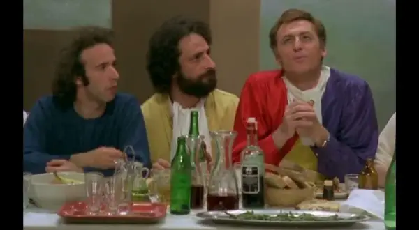 Il cast de "Il Pap'occhio" a tavola, tra bottiglie di vino e pane.