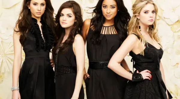 Il cast di Pretty Little Liars posa in abiti eleganti neri su uno sfondo floreale.