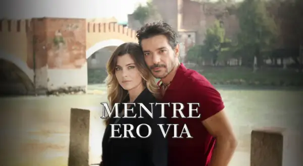 Coppia abbracciata con un ponte sullo sfondo. Il titolo "Mentre ero via" suggerisce una storia di assenza e ritorno.