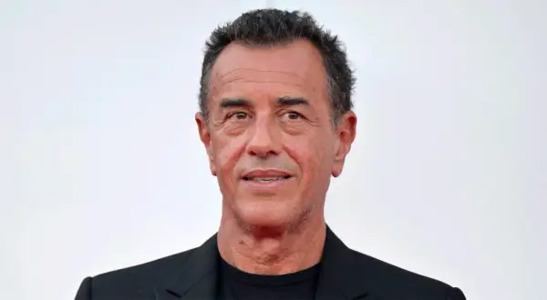 Matteo Garrone, regista italiano, con un sorriso enigmatico. La sua carriera è segnata da film potenti e visivamente sorprendenti.