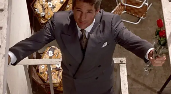 Richard Gere, iconico in "American Gigolo film", con un mazzo di rose rosse, elegante in abito grigio.