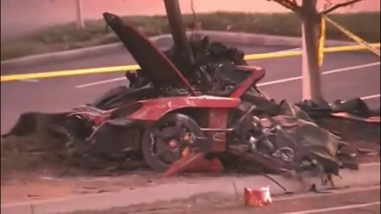 Resti di un'auto rossa distrutta, scena di un tragico incidente che ricorda la paul walker morte. Nastro giallo di delimitazione.